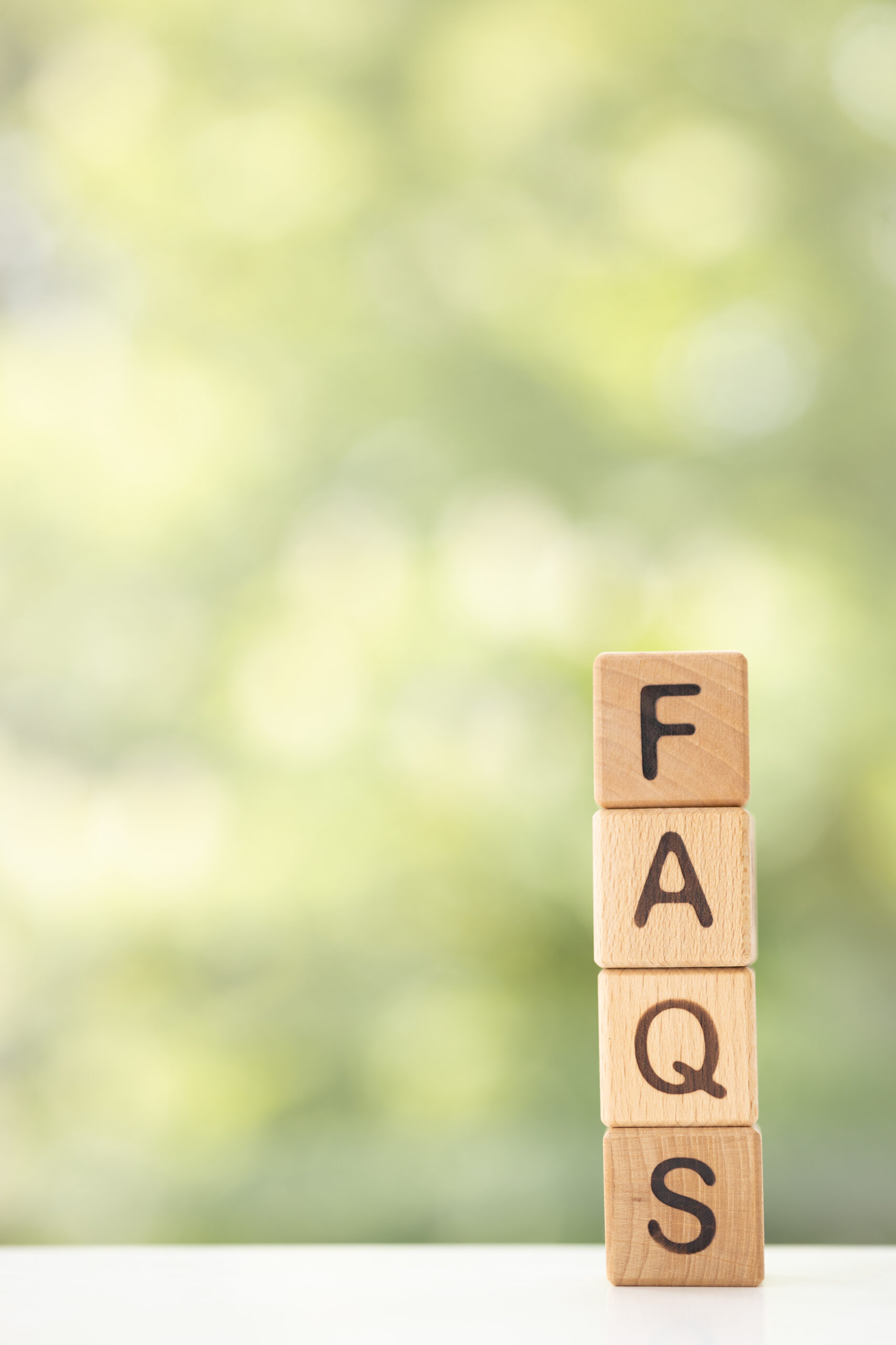 FAQS - word is written on wooden cubes on a green summer background. Close-up of wooden elements.