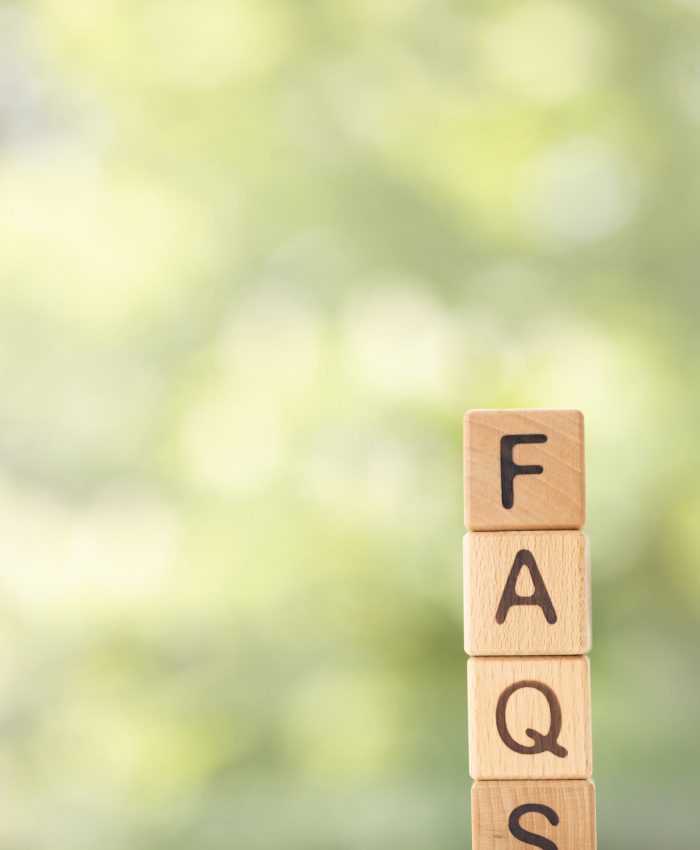 FAQS - word is written on wooden cubes on a green summer background. Close-up of wooden elements.