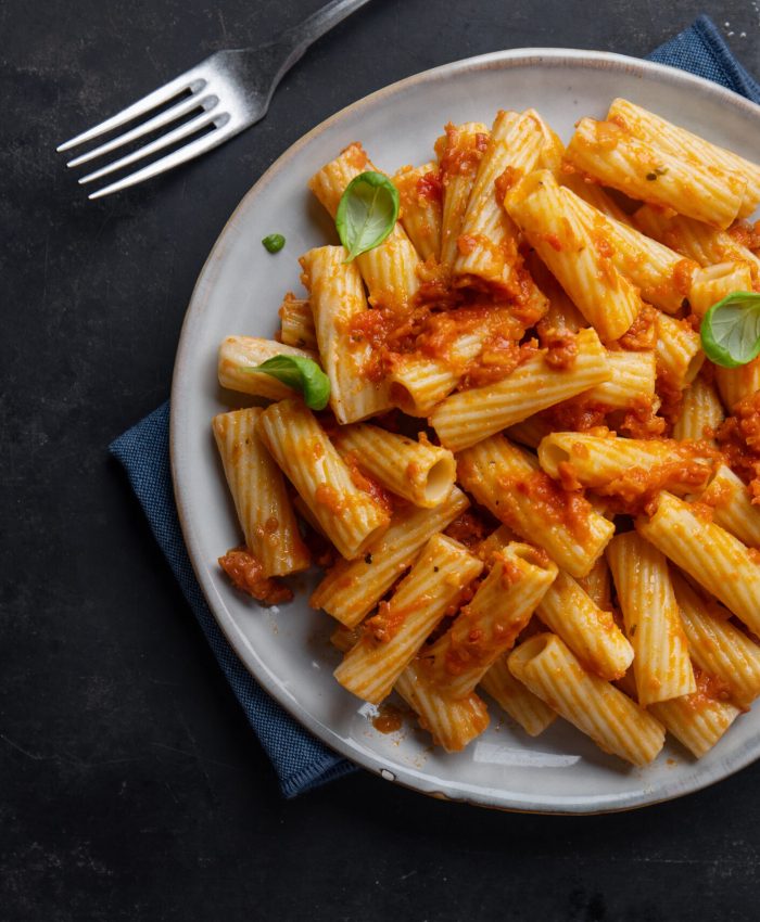 Pasta with tomato sauce chicken and basil served in bowl. Closeup